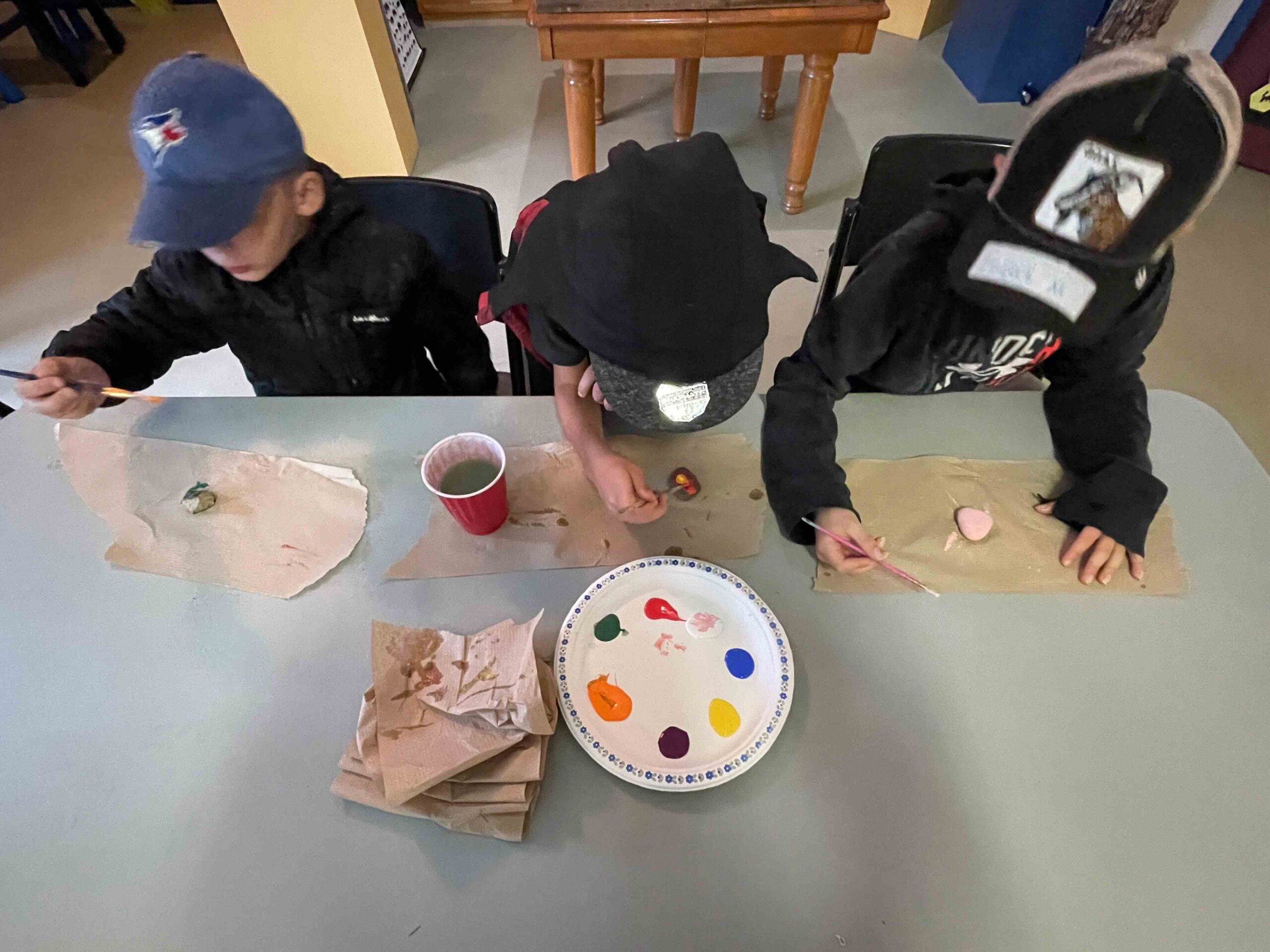 three kids painting rocks